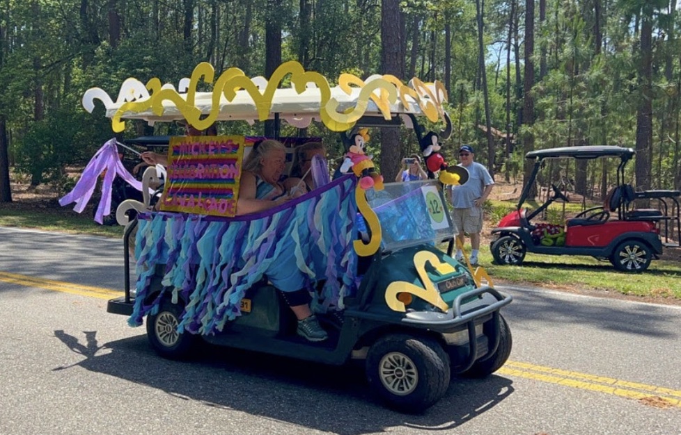 A golf cart decorated with lights and other decorations for a parade